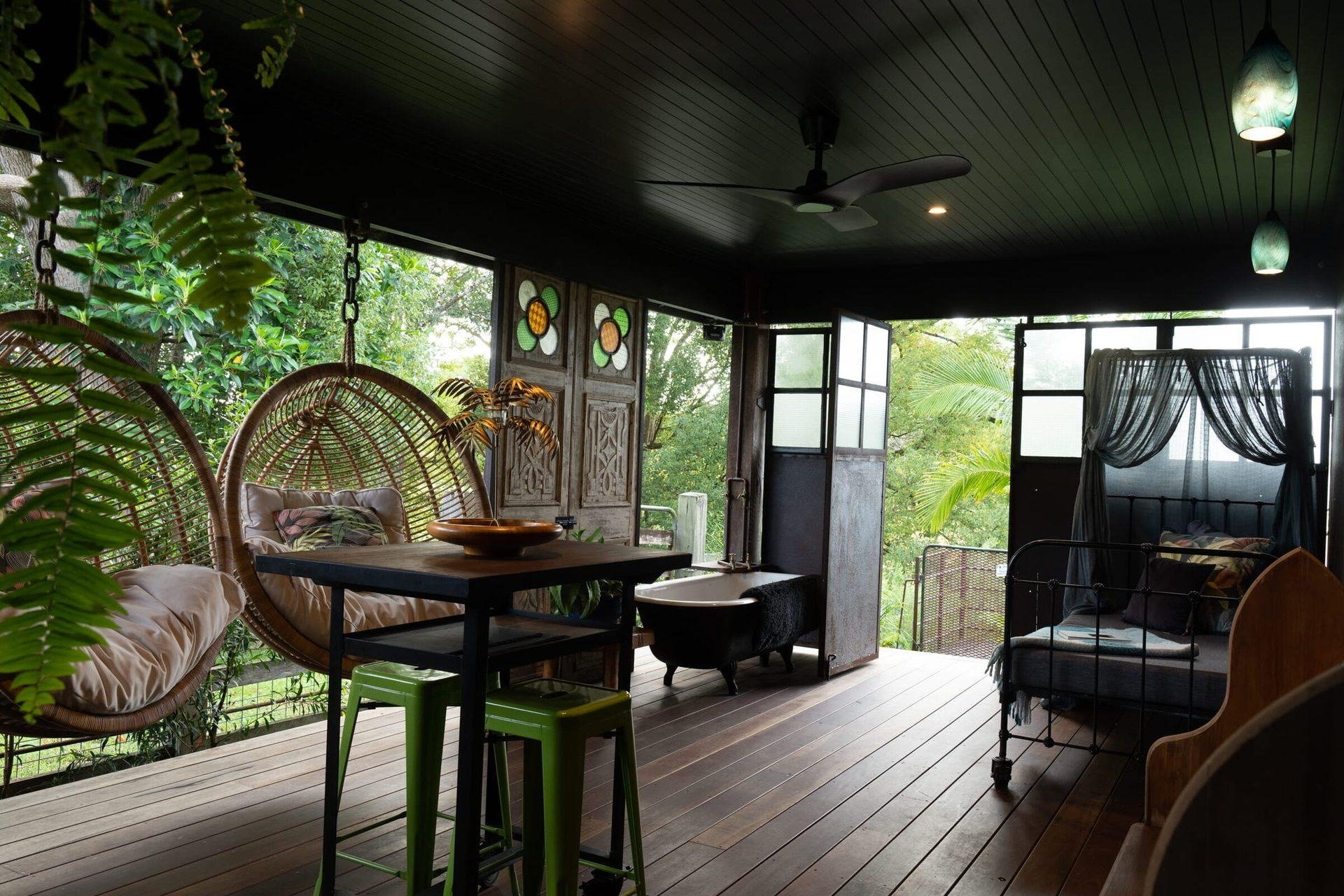 The Barnita covered deck with hanging chairs, a daybed and an antique bathtub