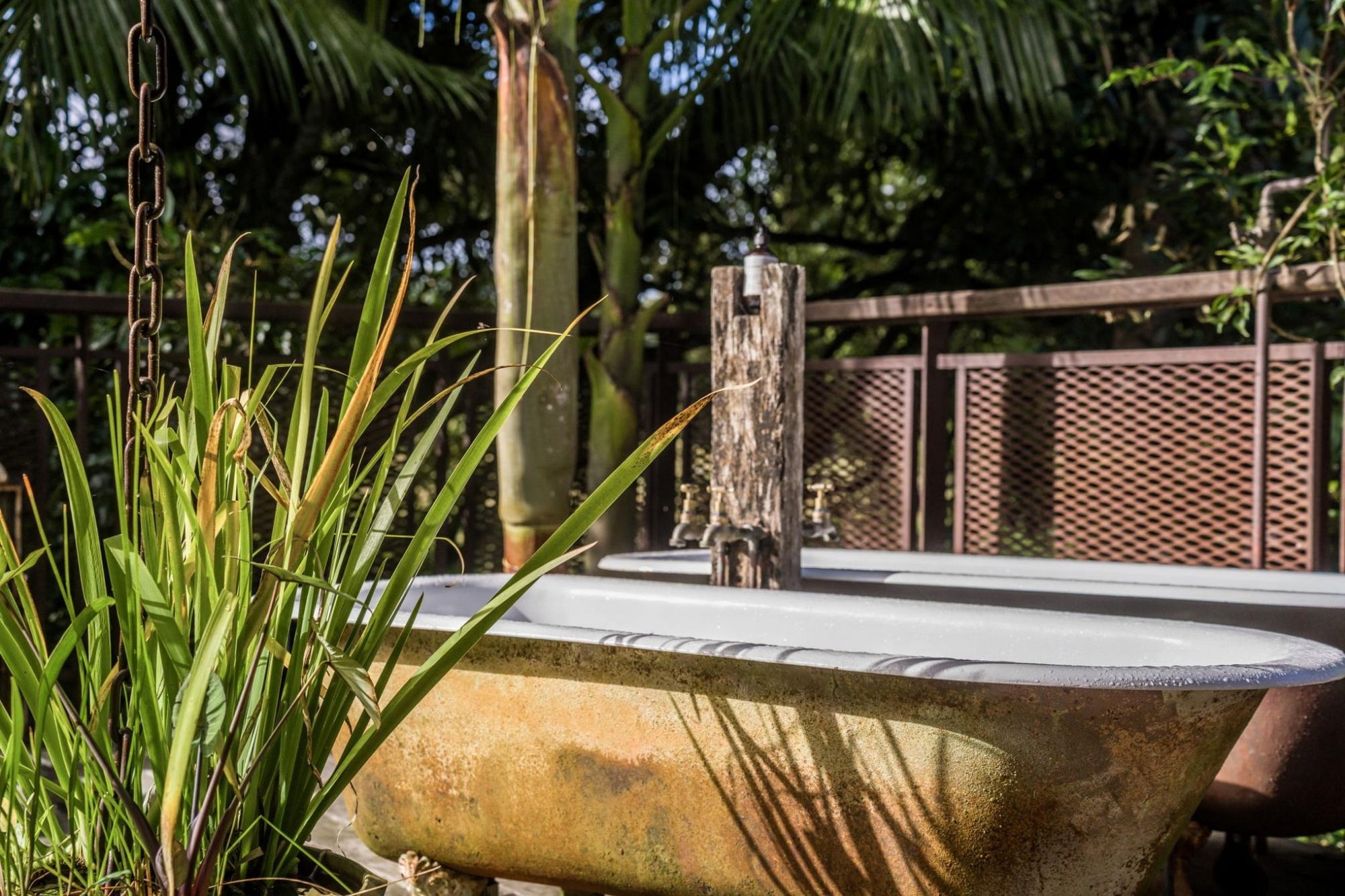 An outdoor claw-foot tub on the barn deck surrounded by grasses