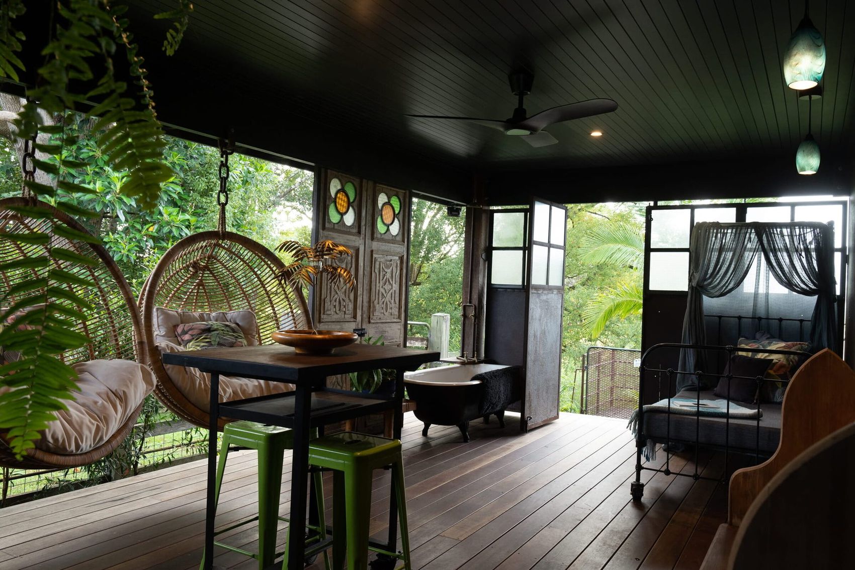 the deck — rattan chairs, iron bed, black tub, all of it